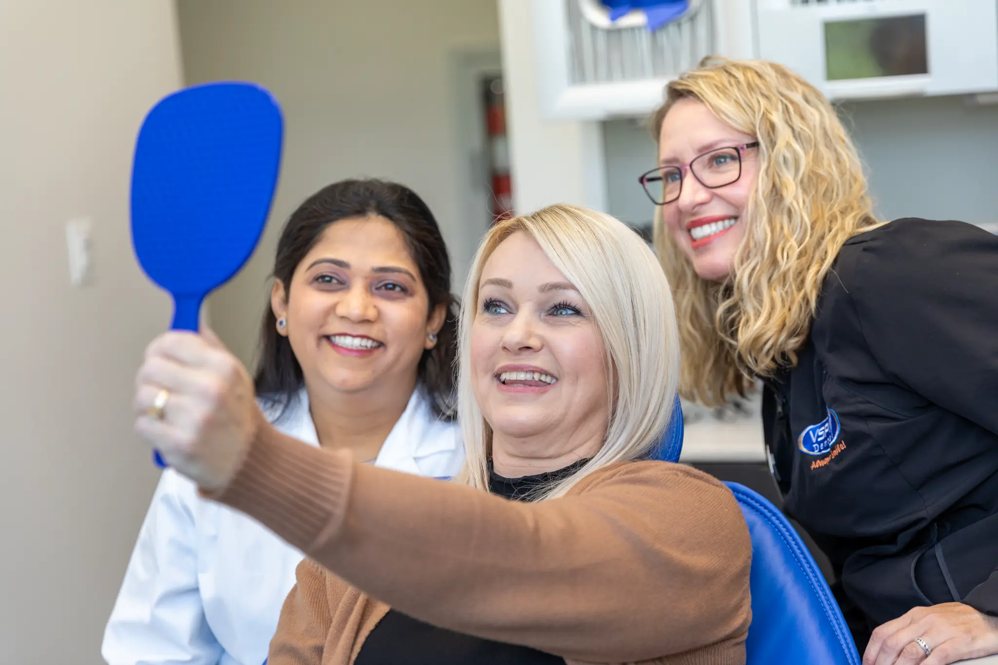 VSP Dental team and patient reviewing her smile with a hand mirror