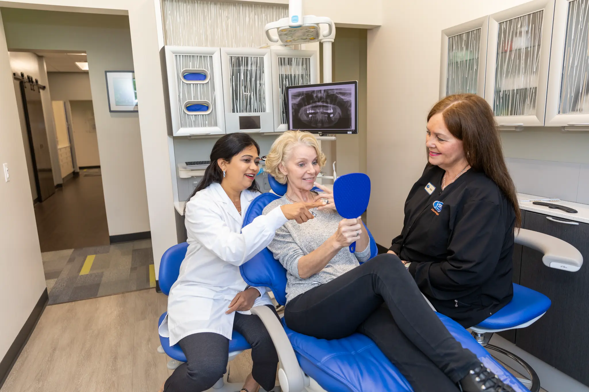 VSP Dental team member and patient reviewing her smile with a hand mirror