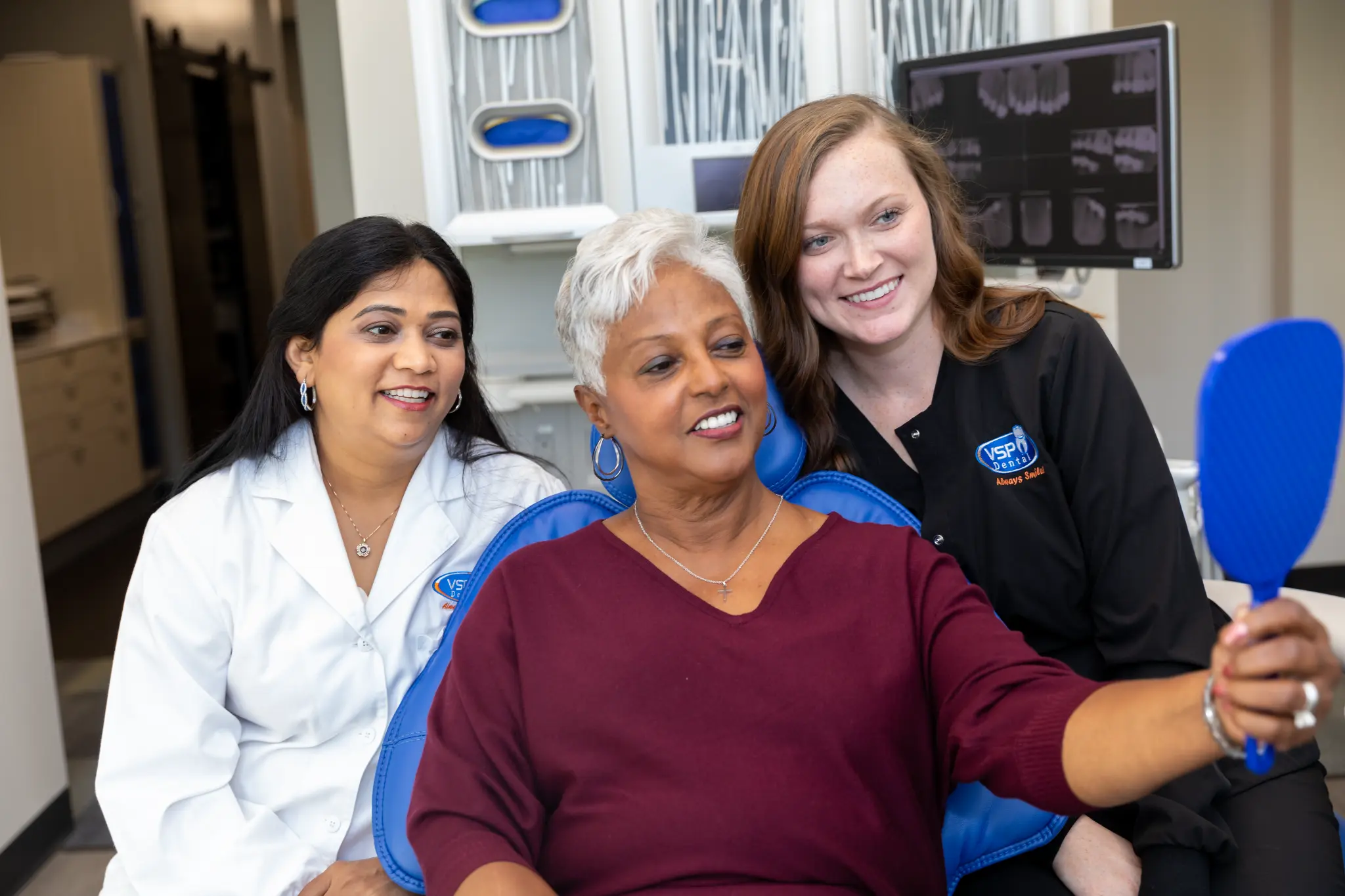 VSP Dental patient looking at her smile in a hand mirror