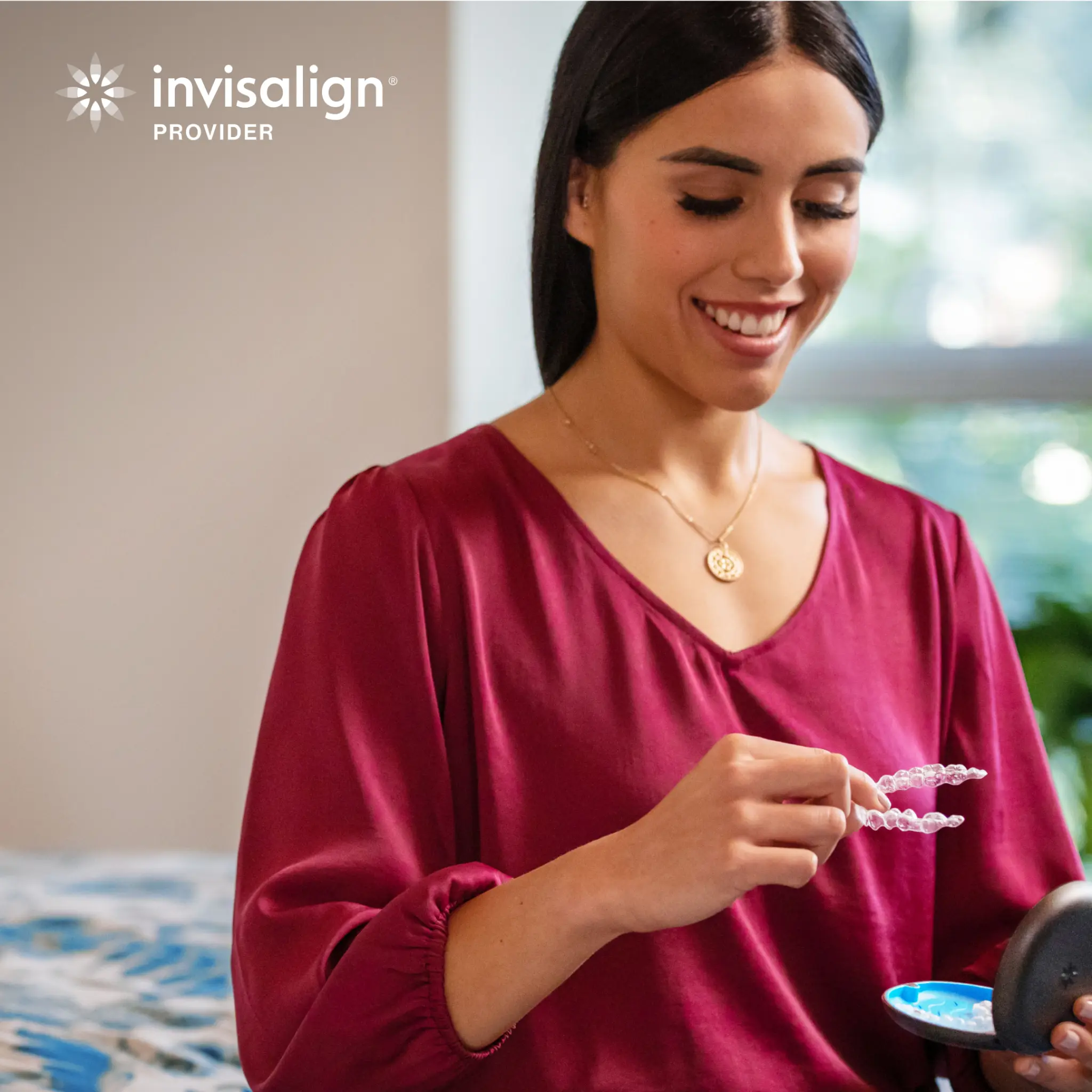 Invisalign patient holding clear aligners during her daily routine
