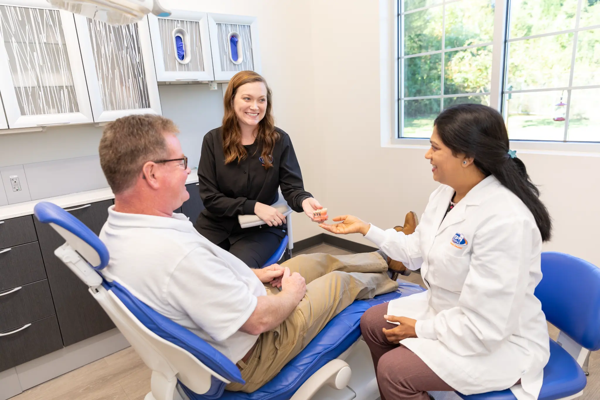 Dr. Vaibhavi Patel with a patient and dental assistant
